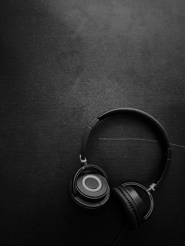 Minimalist black and white photo of headphones on a dark background.