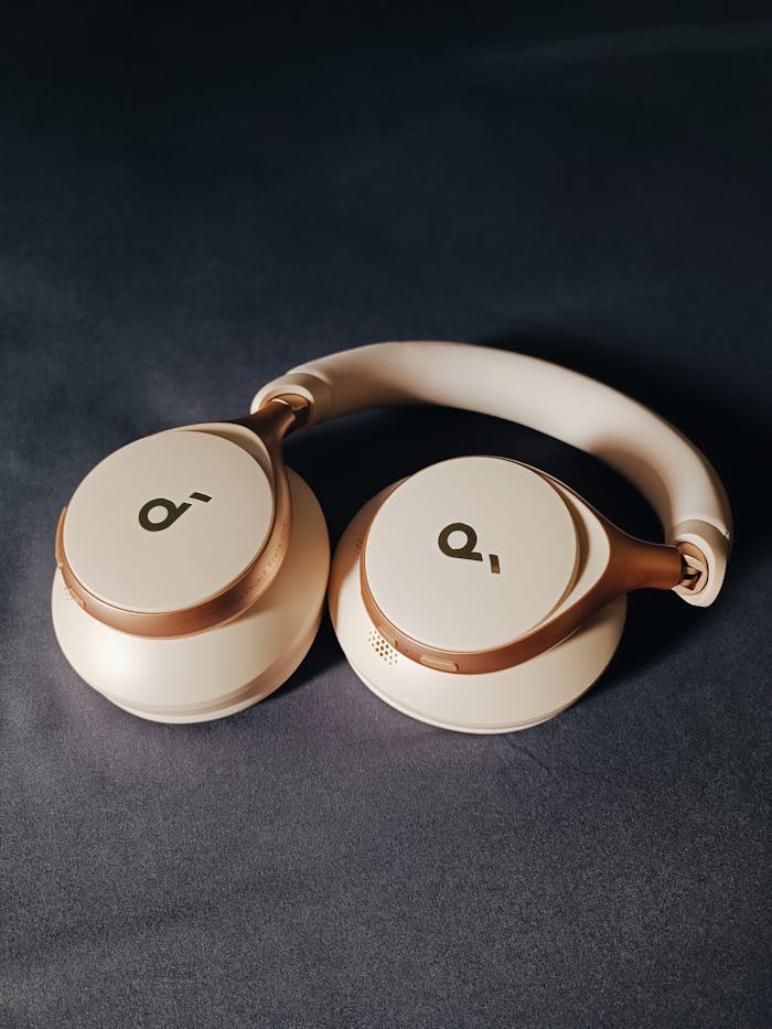 Modern beige wireless headphones on a dark surface, perfect for tech lovers.